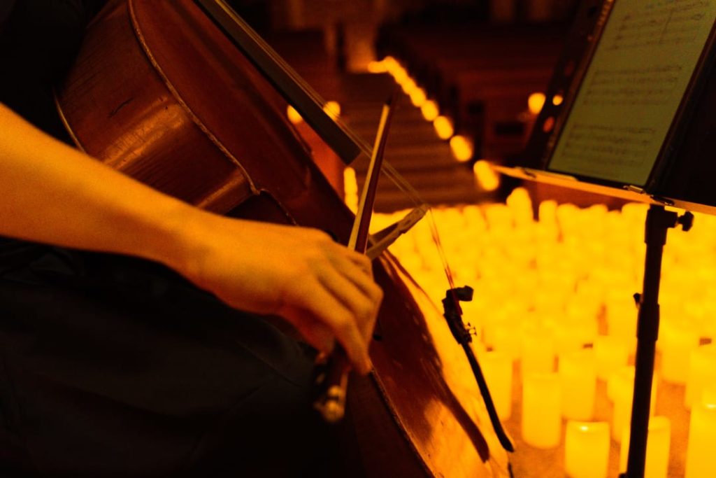 Gros plan d'une femme jouant du violoncelle lors d'un concert Candlelight entourée de bougies