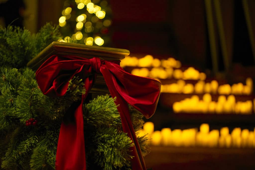 Photo d'un escalier recouvert de bougies et décoré de branches de sapin et d'un ruban rouge pour Noël